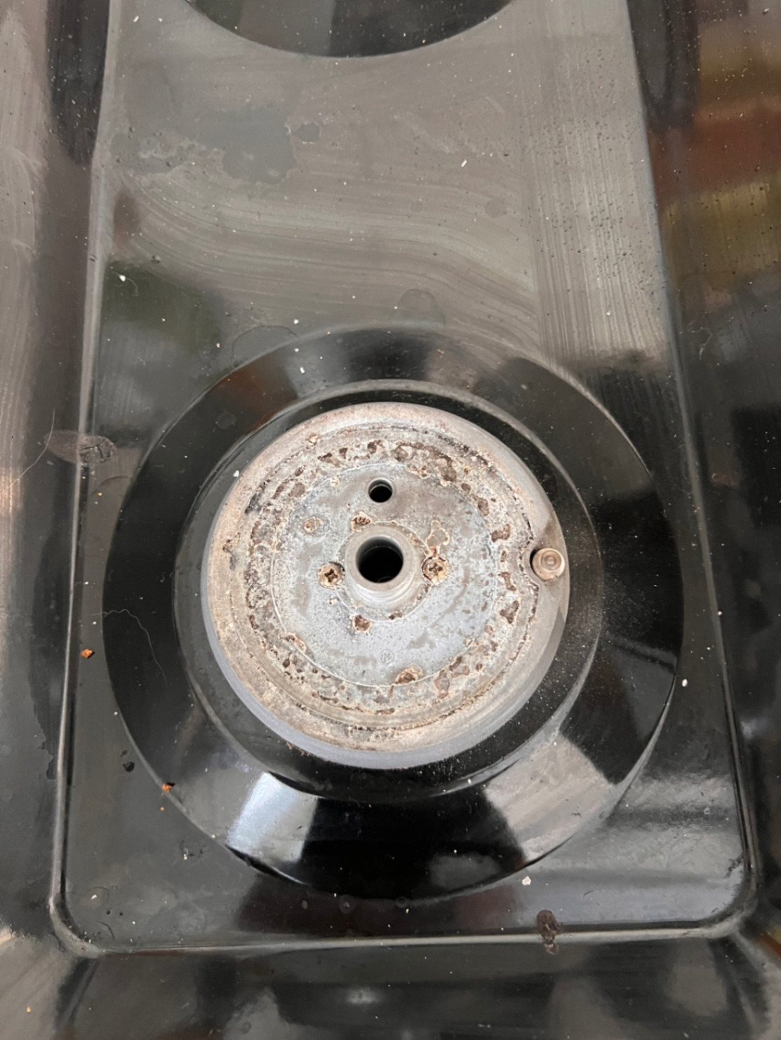 Close-up of stove burner base showing wear and repair condition